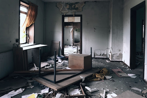 Image of distressed room. Paint is peeling and furniture is tossed across the room.