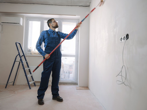 Man painting a wall in a room for a fix-and-flip.